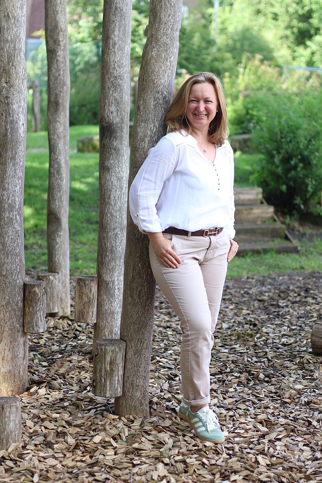 Svetlana Heidt in einem Garten, angelehnt an einen Holzpfahl